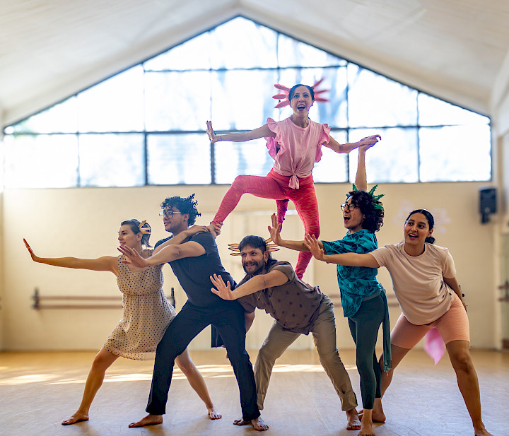 Escena de la obra: el elenco sostiene en alto a una intérprete
