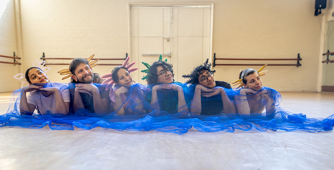 El elenco tendido sobre la tela azul que hace de agua del canal